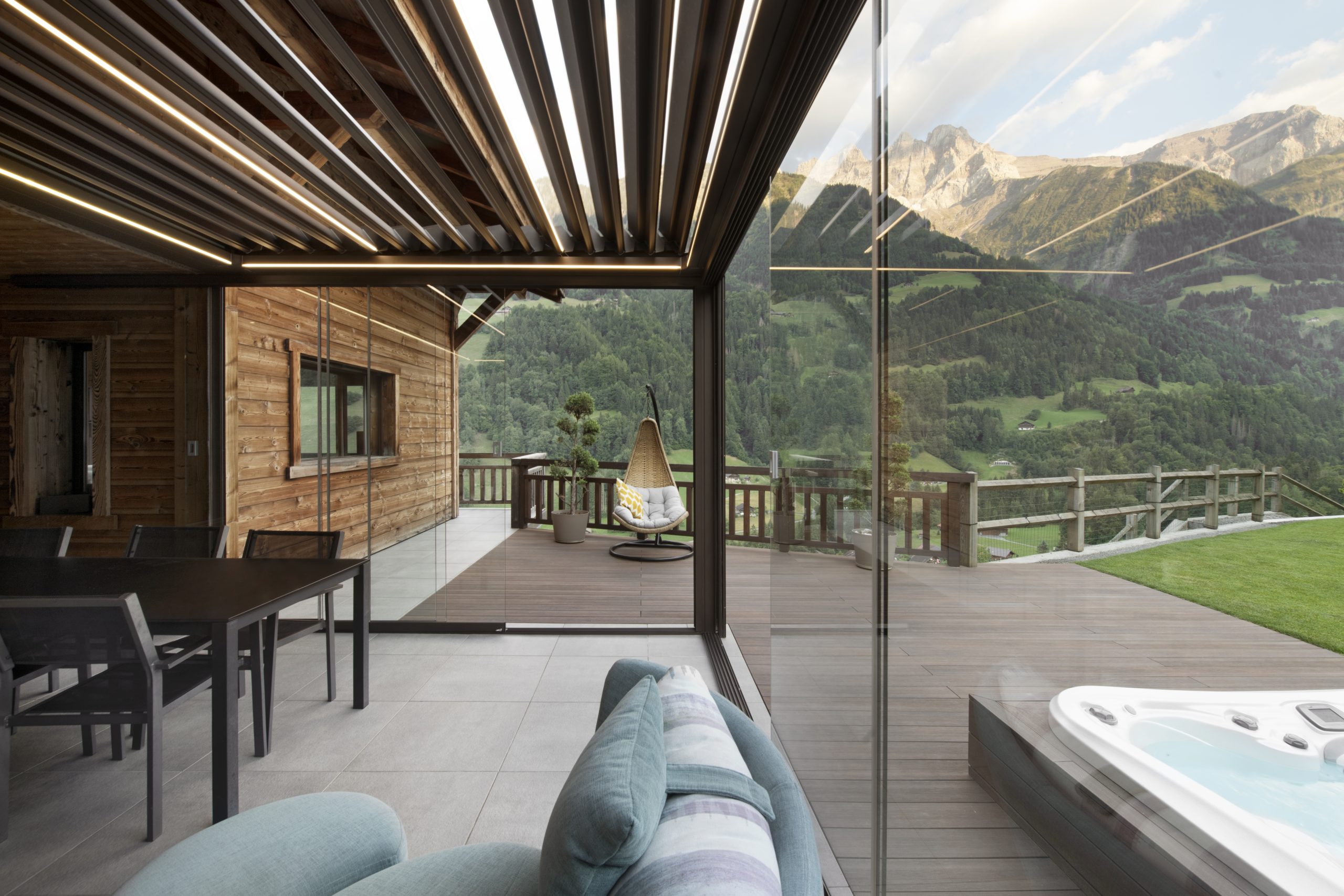 Pergotenda bioclimatica color legno sul terrazzo di una villa collocata di fronte ad un paesaggio in montagna